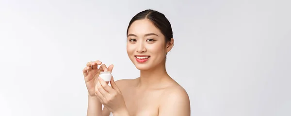 Bella giovane donna su sfondo bianco isolato che tiene crema cosmetica viso, asiatico — Foto Stock