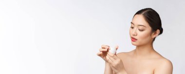 Beyaz, soyutlanmış arka planda güzel bir kadın elinde kozmetik yüz kremi, Asyalı