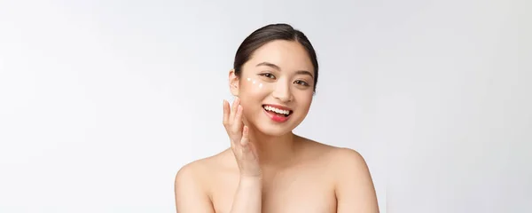 피부는 미녀를 돌봅니다. 미녀가 크림바르면서 웃고 있어. 흰색에 고립된 아름다운 아시아인 여성 모델의 아름다운 초상화. — 스톡 사진
