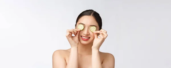 天然自家製新鮮なキュウリのフェイシャルアイパッドフェイシャルマスク。キュウリのパッドを持つアジアの女性と笑顔は、自然の自家製でリラックス — ストック写真