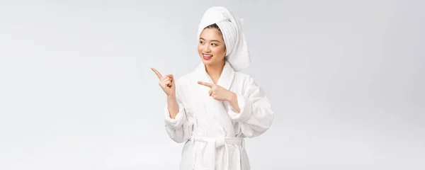 Schoonheidsportret van jonge vrouw tonen en wijsvinger naar lege kopieerruimte, aziatische schoonheid in badjas. — Stockfoto