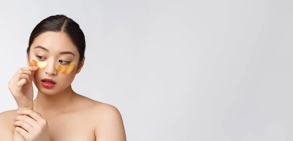 Ázsiai szépség tinédzser nő törődik a bőrét arany szem maszkok foltok alatt szem — Stock Fotó