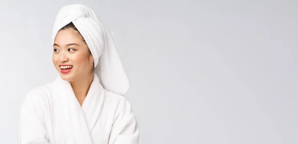 Portret van een jonge gelukkige aziatische dame in badjas. Geïsoleerd in witte achtergrond. — Stockfoto