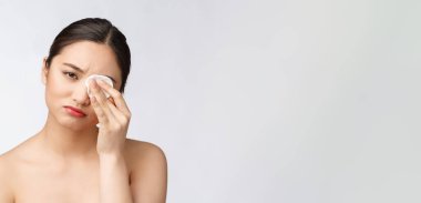 Cilt bakımı yapan kadın yüz makyajını pamuklu bezle temizliyor. Cilt bakımı konsepti. Mükemmel ciltli güzel melez ırk modelinin yüz görüntüsü..