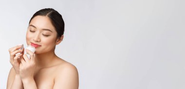 Beyaz, soyutlanmış arka planda güzel bir kadın elinde kozmetik yüz kremi, Asyalı