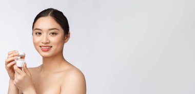 Beyaz, soyutlanmış arka planda güzel bir kadın elinde kozmetik yüz kremi, Asyalı