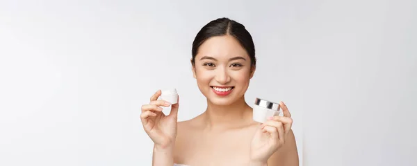 Beyaz, soyutlanmış arka planda güzel bir kadın elinde kozmetik yüz kremi, Asyalı — Stok fotoğraf