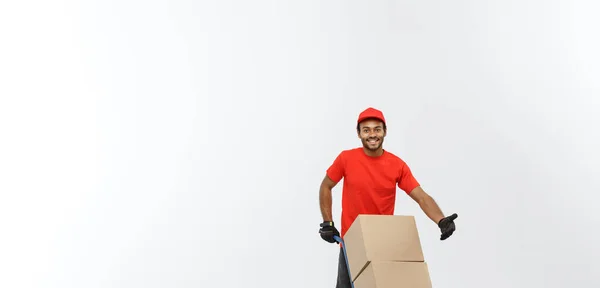 Delivery Concept - Portrait of Handsome African American delivery man or courier pushing hand truck with stack of boxes. Isolated on Grey studio Background. Copy Space. — Stock Photo, Image