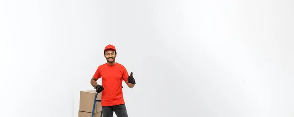 Delivery Concept - Portrait of Handsome African American delivery man or courier pushing hand truck with stack of boxes. Isolated on Grey studio Background. Copy Space. — Stock Photo, Image
