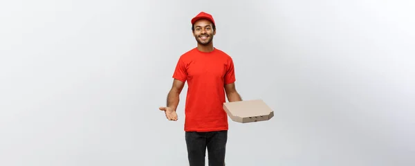 Koncepcja dostawy - portret szczęśliwy African American dostawy człowiek kształt dłoni, aby przedstawić pakiet pole pizza. Na białym tle na studio szary tło. Miejsce. — Zdjęcie stockowe