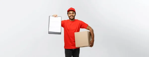 Concepto de entrega - Retrato del guapo repartidor afroamericano o mensajero que muestra un formulario de documento de confirmación para firmar. Aislado en Grey studio Background. Copiar espacio . —  Fotos de Stock