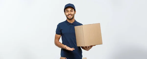 Concepto de entrega - Retrato del repartidor afroamericano feliz señalando mano para presentar un paquete de caja. Aislado en Grey studio Background. Copiar espacio . — Foto de Stock