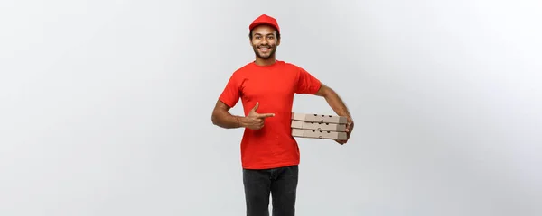 Concepto de entrega - Retrato del repartidor afroamericano feliz señalando mano para presentar un paquete de caja. Aislado en Grey studio Background. Copiar espacio . — Foto de Stock