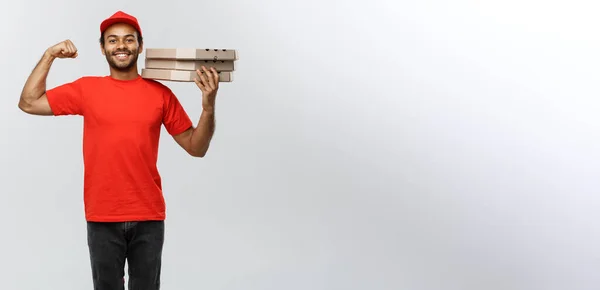 Koncepcja dostawy - Portret mężczyzny dostawy Strong African American Wyświetlono jego mięśni z pizza box pakietów. Na białym tle na studio szary tło. Miejsce. — Zdjęcie stockowe