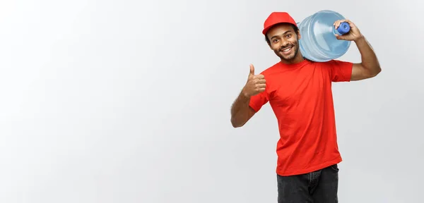 Concepto de entrega - Guapo repartidor afroamericano que sostiene el tanque de agua. Aislado en Grey studio Background. Copiar espacio . —  Fotos de Stock