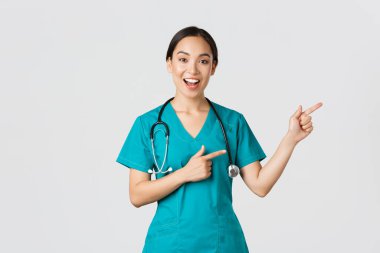 Covid-19, sağlık çalışanları, salgın konsepti. Gülümseyen, güzel Asyalı doktor, önlüklü kadın terapist ya da sağ üst köşeyi gösteren hemşire, hastanın beyaz geçmişini gösteriyor.