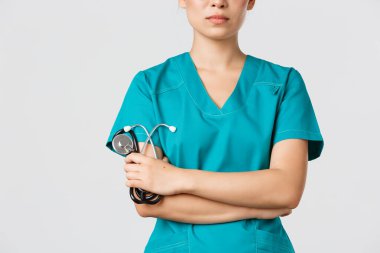 Covid-19, koronavirüs hastalığı, sağlık çalışanları konsepti. Kendine güvenen Asyalı doktor, tıbbi önlüklü doktor, çapraz kollar saptanmış ve steteskop tutuyor.