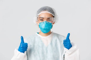 Covid-19, koronavirüs hastalığı, sağlık çalışanları konsepti. Kendine güvenen profesyonel Asyalı doktor, teknoloji laboratuarı çalışanı kişisel koruma ekipmanları onaylandı.