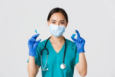 Covid-19, koronavirüs hastalığı, sağlık çalışanları konsepti. Yakışıklı, gülümseyen Asyalı kadın hemşire, aşı ampul ve şırınga gösteren doktor, enjeksiyona hazır olun, beyaz arka plan.
