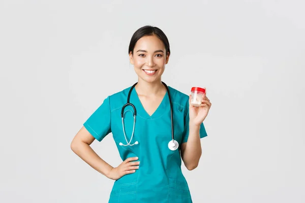 Zdravotničtí pracovníci, prevence viru, koncepce karanténní kampaně. Usmívající se hezká asijská žena lékař, zdravotní sestra v křoví ukazuje pilulky, doporučit léky nebo vitamíny, bílé pozadí — Stock fotografie