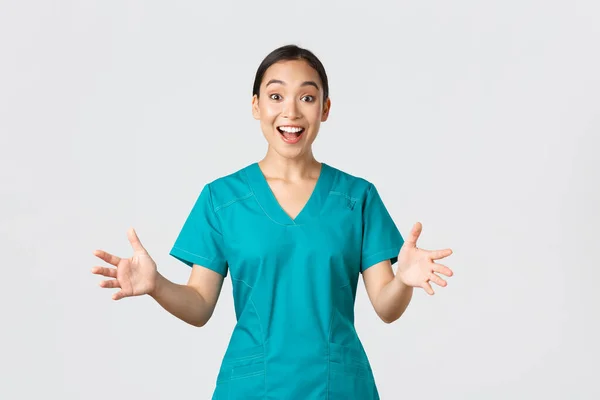 Covid-19, egészségügyi dolgozók, világjárvány. Boldog és meglepett ázsiai nővér köpenyben felemeli a kezét izgatott és mosolygó. Az orvos gratulál nagy hír, taps, fehér háttér — Stock Fotó