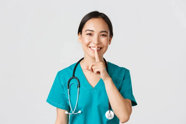 Gesundheitshelfer, Virusprävention, Kampagnenkonzept für Quarantäne. Lächelnder hübscher asiatischer Arzt, Krankenschwester im Peeling lächelnd, schreiend, fordernd, ruhig zu bleiben, weißer Hintergrund stehend — Stockfoto