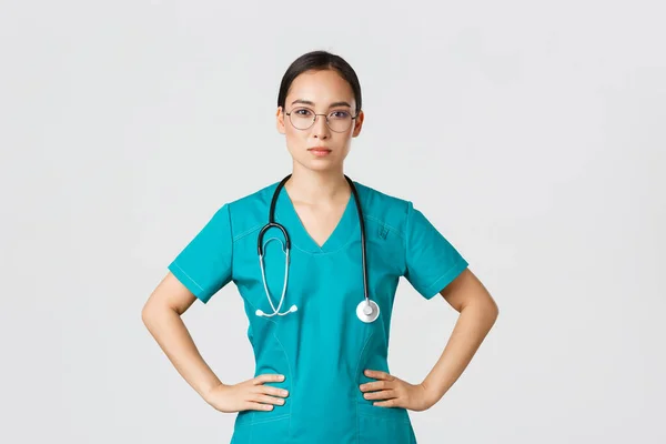Covid-19, zdravotníci, pandemický koncept. Sebevědomá odhodlaná asijská ošetřovatelka pomáhá pacientům, pracuje s koronavirovou chorobou, připravuje se, má na sobě pláště a brýle, bílé pozadí — Stock fotografie