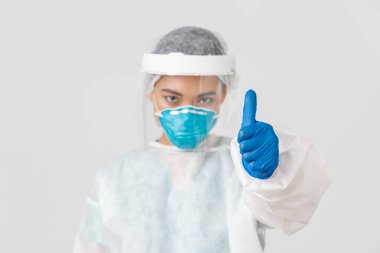 Covid-19, koronavirüs hastalığı, sağlık çalışanları konsepti. Ciddi görünümlü, kendine güvenen Asyalı kadın doktor, solunum cihazında kişisel koruyucu ekipman hekimi, baş parmaklarını yukarı kaldır, beyaz arka plan