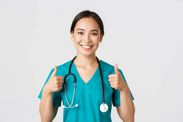 Healthcare workers, preventing virus, quarantine campaign concept. Close-up of upbeat smiling asian doctor, physician looking confident, ensure patient, showing thumbs-up in approval — Stock Photo, Image