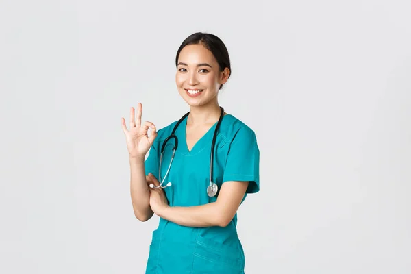 Covid-19, egészségügyi dolgozók, világjárvány. Magabiztos, hivatásos ázsiai orvos, köpenyes női orvos, aki jó gesztust mutat, garantálja a kórházi szolgáltatások minőségét, jóváhagyja és elfogadja — Stock Fotó