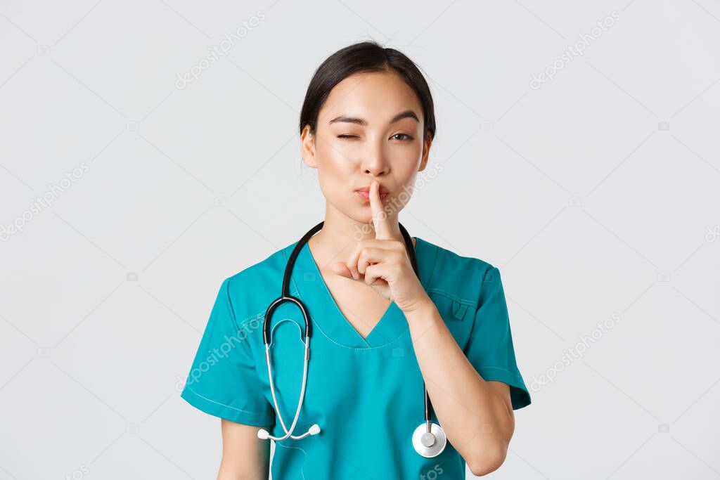 Healthcare workers, preventing virus, quarantine campaign concept. Sassy cute asian female doctor, physician shushing and winking coquettish, have secret, prepare surprise, asking keep quiet
