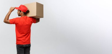 Teslimat kavramı - yakışıklı African American teslimatçı kutu paket ile Arkadan Görünüm. Arka plan gri studio izole. Kopya alanı.