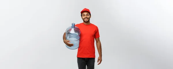 Doručení koncept - hezký afroamerické doručovatel zásobník vody. Izolované na šedé studio pozadí. Kopírovat prostor. — Stock fotografie