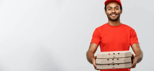 Concetto di consegna Ritratto di bello afroamericano Pizza uomo di consegna. Isolato su sfondo grigio studio. Copia spazio. — Foto Stock