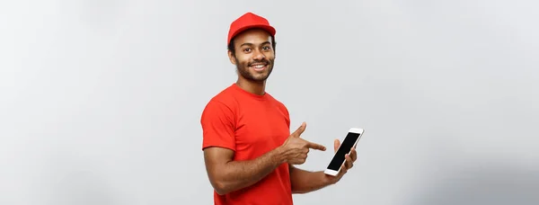 Concepto de entrega: retrato del guapo repartidor afroamericano o mensajero que le muestra la tableta para verificar el pedido. Aislado en Grey studio Background. Copiar espacio . — Foto de Stock