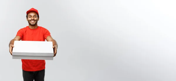 Concepto de entrega - Retrato del guapo repartidor de pizza afroamericana. Aislado en Grey studio Background. Copiar espacio . —  Fotos de Stock