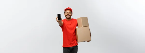 Delivery Concept - Portrait of Handsome African American delivery man or courier with box showing mobile phone on you to check the order. Isolated on Grey studio Background. Copy Space. — Stock Photo, Image