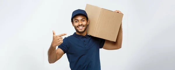 Delivery Concept - Portrait of Happy African American delivery man pointing hand to present a box package. Isolated on Grey studio Background. Copy Space. — Stock Photo, Image