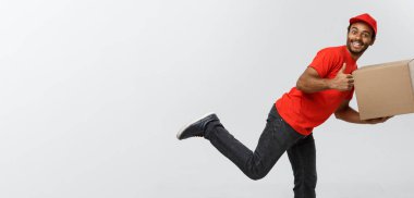 Teslimat kavramı - müşteri için bir paketi teslim etmek için çalışan yakışıklı Afro-Amerikan teslimat adam acele. Arka plan gri studio izole. Kopya alanı.