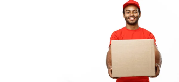 Lieferkonzept - Porträt eines glücklichen afrikanisch-amerikanischen Zustellers in rotem Tuch, der ein Karton-Paket hält. isoliert auf weißem Studiohintergrund. Kopierraum — Stockfoto