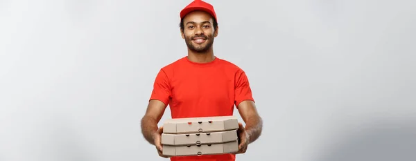 Concepto de entrega - Retrato del guapo repartidor de pizza afroamericana. Aislado en Grey studio Background. Copiar espacio . —  Fotos de Stock