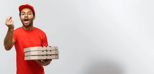 Παράδοση έννοια - πορτρέτο του Happy αφρικανική αμερικανική άνθρωπος παράδοσης δείχνει νόστιμο χειρονομία με το χέρι με holding κουτιά από πίτσα πακέτο. Απομονωμένη στο στούντιο γκρι φόντο. Χώρο αντίγραφο. — Φωτογραφία Αρχείου