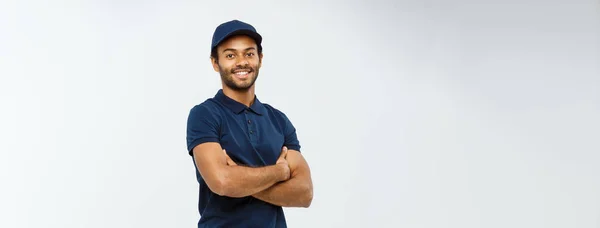 Concetto di consegna - Bello uomo di consegna afroamericano incrociato le braccia oltre isolato su sfondo grigio studio. Copia spazio. — Foto Stock