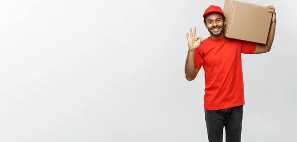 Delivery Concept - Portrait of Happy African American delivery man holding a box package and showing ok sign. Isolated on Grey studio Background. Copy Space. — Stock Photo, Image