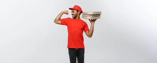 Delivery Concept: Portrait of Strong African American delivery man menunjukkan ototnya dengan paket kotak pizza. Terisolasi di Grey studio Background. Salin Ruang . — Stok Foto