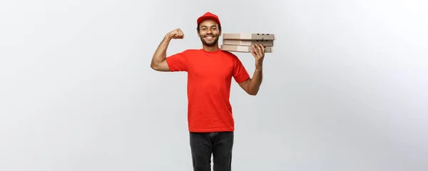 Concetto di consegna Ritratto di forte uomo di consegna afroamericano che mostra il suo muscolo con pacchetti di scatole di pizza. Isolato su sfondo grigio studio. Copia spazio . — Foto Stock