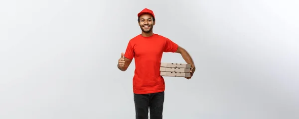 Conceito de entrega - Retrato de homem de entrega afro-americano feliz segurando embalagens de caixa e mostrando thumps para cima. Isolado no estúdio Grey Background. Espaço de cópia . — Fotografia de Stock