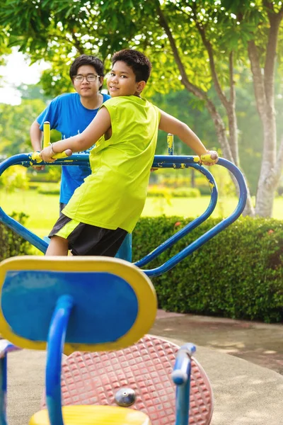 Child playing on outdoor playground. Kids play on school or kindergarten yard. Active kid on colorful swing. Healthy summer activity for children. Little boy swinging in tropical garden