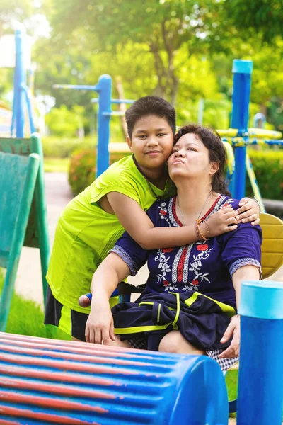 Küçük şirin Asyalı çocuk sarılmak annesi ve kamera mutlu zaman gülümseyen.