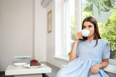 Genç güzel beyaz Bayan zevk içme ve tatlı modern kahve dükkanında öğlen sahip..